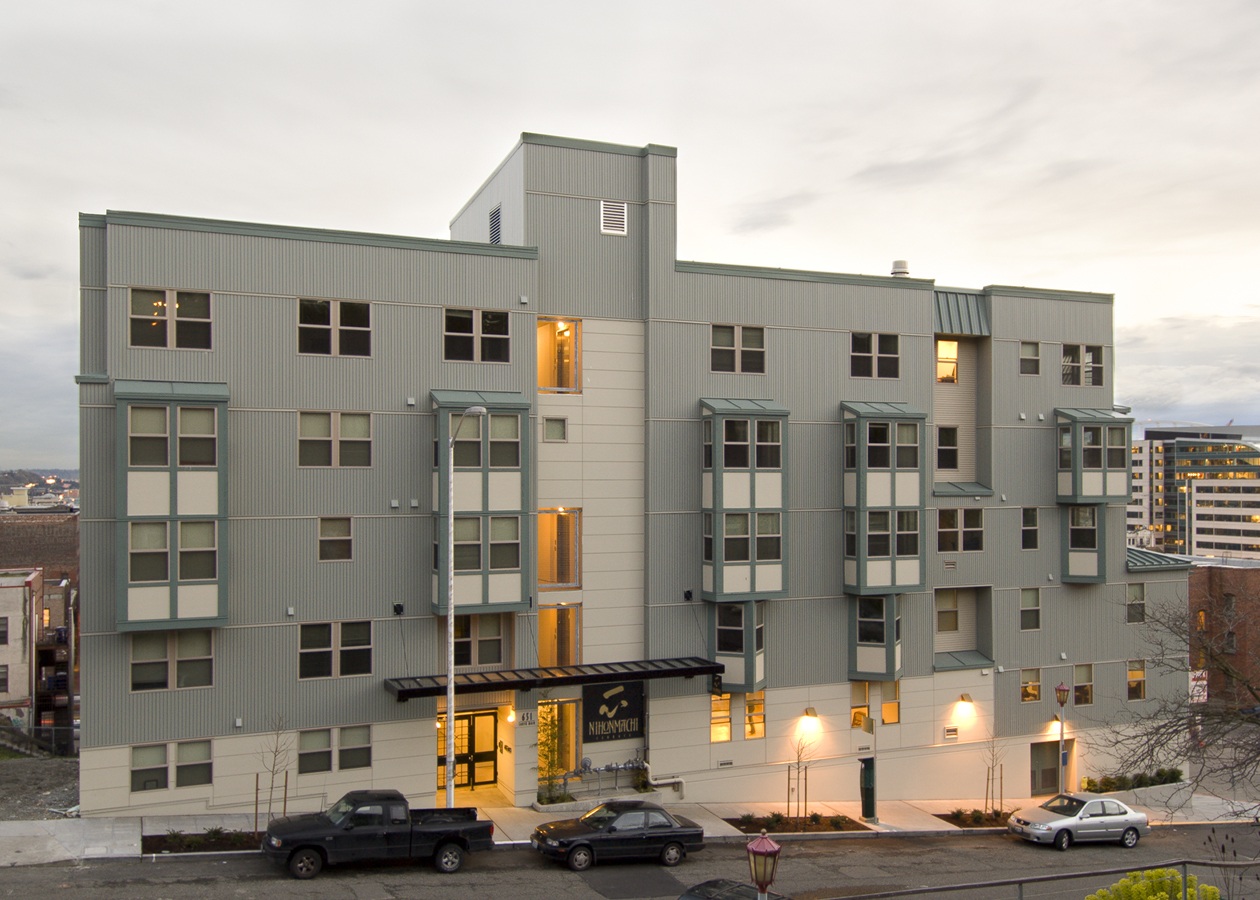 A grey building with a black truck parked in front.